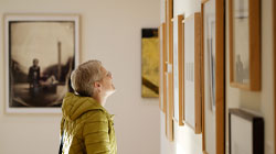 A woman looking at photographs in the permanent wing of the museum.